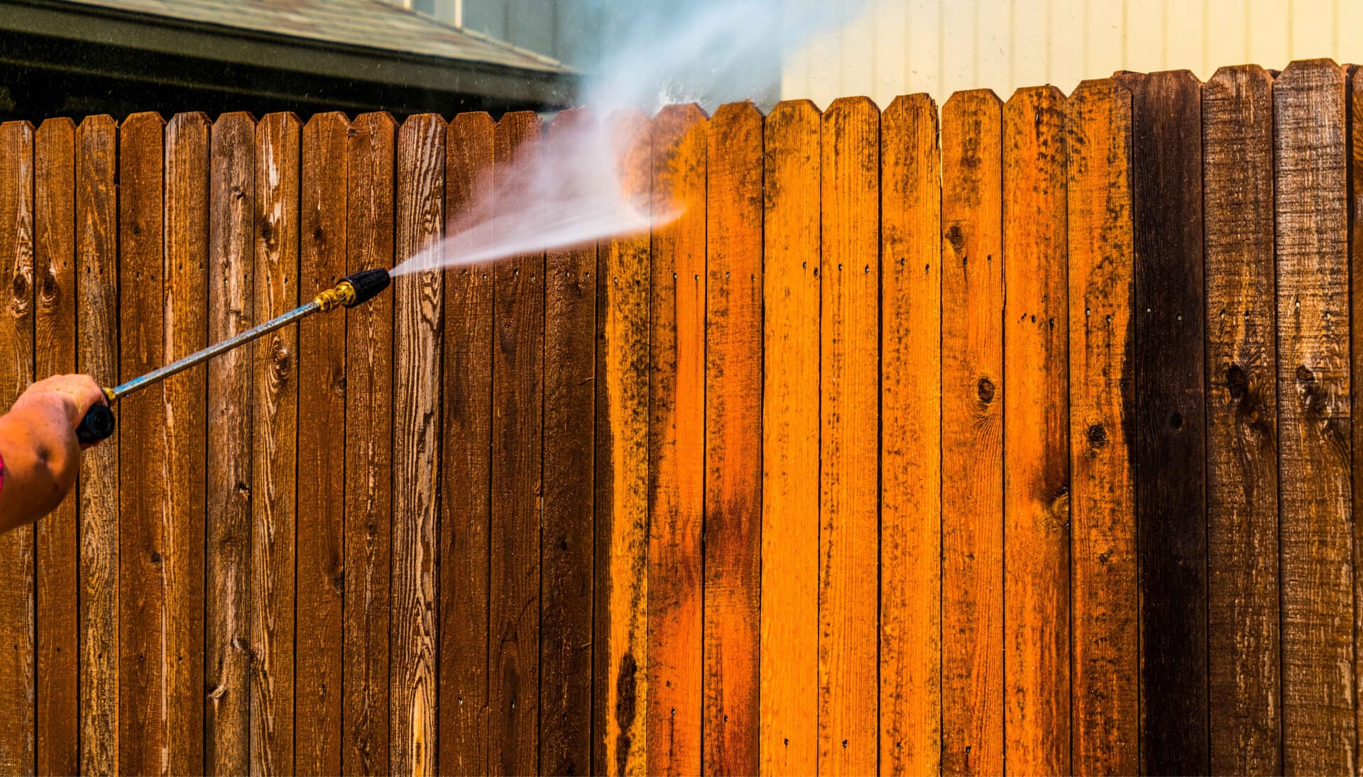 A professional applying stain to a wooden fence in San Antonio, enhancing its natural beauty and protecting it from the elements